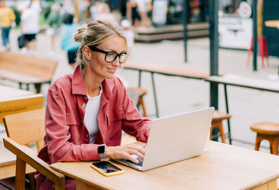 Young woman using laptop while sitting on table