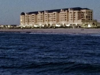 Sea by houses against sky at night