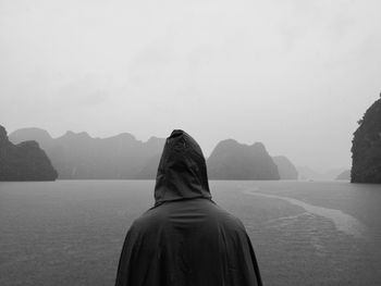 Rear view of man looking at mountains against sky