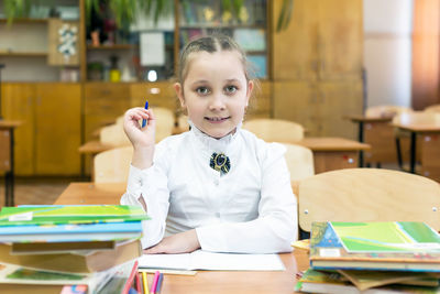 Portrait of girl sitting by books on table