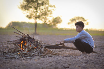 Side view of young man sitting on field