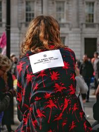 Rear view of woman with text on street in city