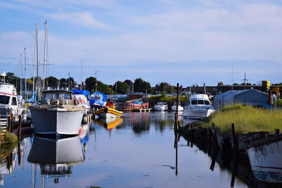 Boats moored at harbor against sky