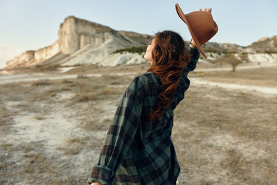 Rear view of young woman standing against sky