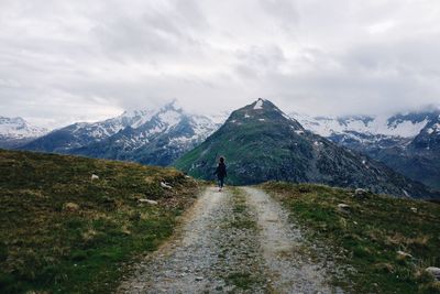 Rear view of man walking on mountain against sky