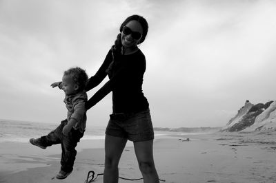 Mother and son playing at beach against sky