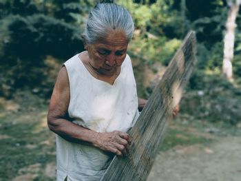 Midsection of woman with arms raised standing against trees