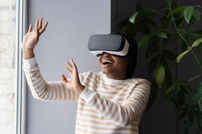 Overjoyed african woman spending leisure time in virtual reality while relaxing at home