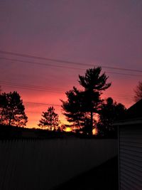 Silhouette trees and building against sky during sunset