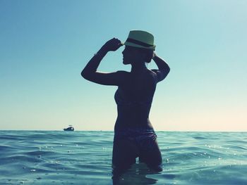 Full length of woman standing in sea against clear sky