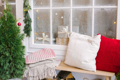 Pillows and a blanket on a bench near the house, decorated for christmas and new year