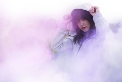 Portrait of young woman standing by smoke