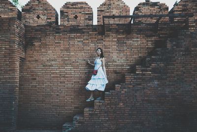 Woman walking on steps by brick wall