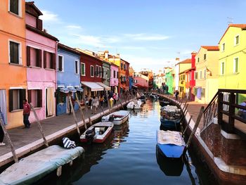 Boats moored on canal amidst buildings in city