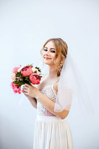 Young woman holding bouquet against white background