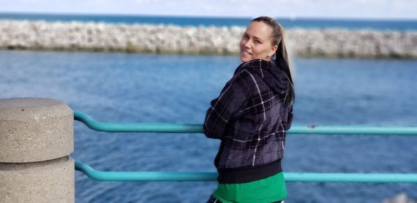 Woman standing by railing against sea