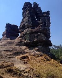 Low angle view of rocky mountains against blue sky