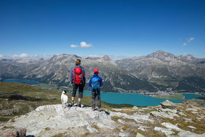 Woman and boy with dog standing on rock while looking at lake silvaplana