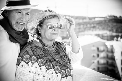 Close-up of couple wearing hat against sky in sunny day