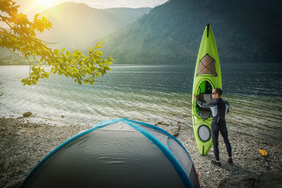 Man holding kayak on shore