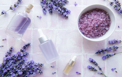 Spa products and lavender flowers on a pink tile background. 