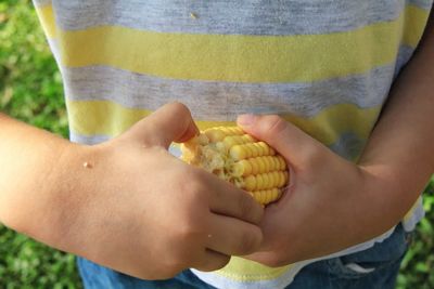 Child holding a corn cob and playing with it