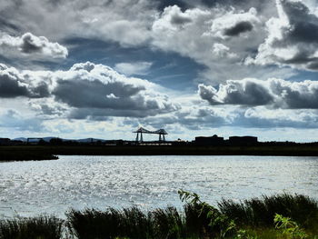 Scenic view of river against cloudy sky