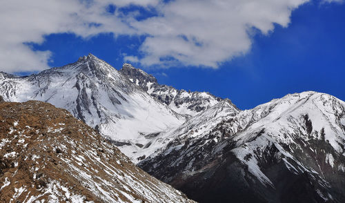 Scenic view of snow covered mountains against cloudy sky