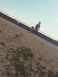 Low angle view of men walking against clear sky