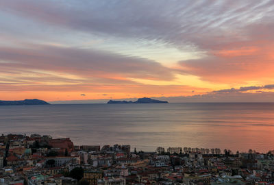 Scenic view of sea by buildings against sky during sunset