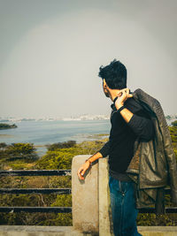 Side view of man standing at bridge against sky