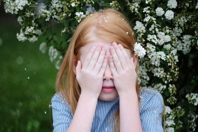 Girl with face covered against plants