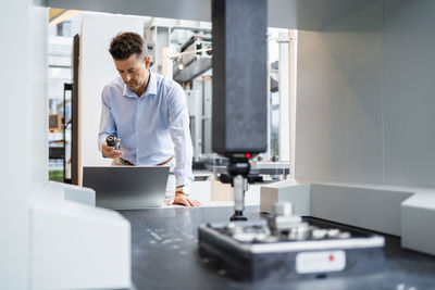 Mature businessman analyzing equipment in front of laptop