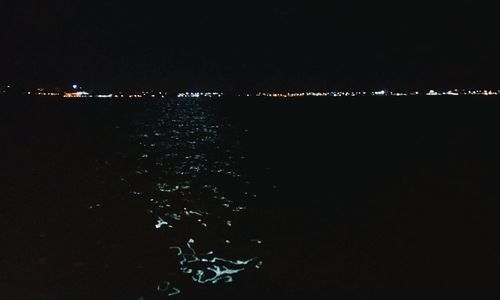 Illuminated sea against clear sky at night