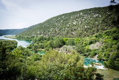 Scenic view of river by mountains against sky