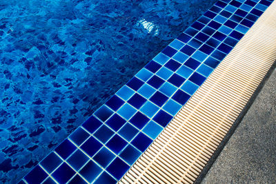 Blue ceramic tile flooring and drainage gutters beside the pool