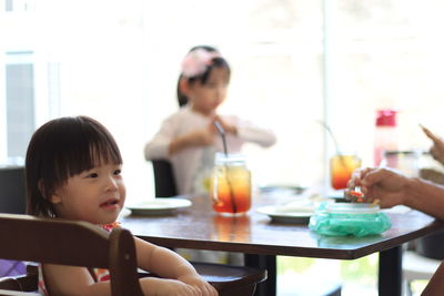 Cute girl sitting on high chair at home