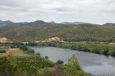 Scenic view of river by mountains against sky