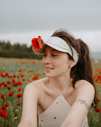 Smiling woman with flower sitting in field
