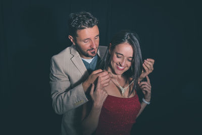 Man wearing necklace to woman against black background