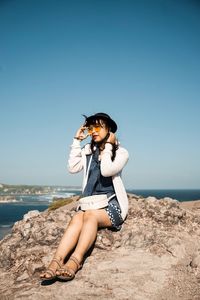 Young woman wearing hat on beach against clear sky