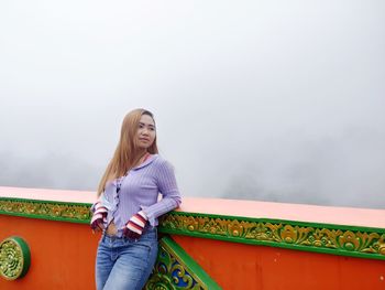 Full length of young woman standing against sky