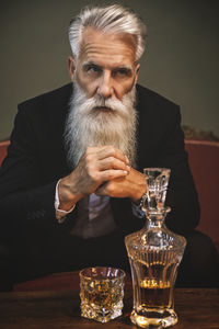 Portrait of senior man drinking glass on table
