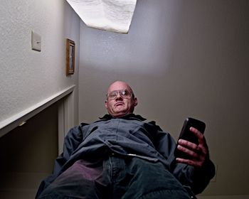 Portrait of man using mobile phone against wall