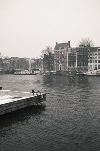 River by buildings against clear sky
