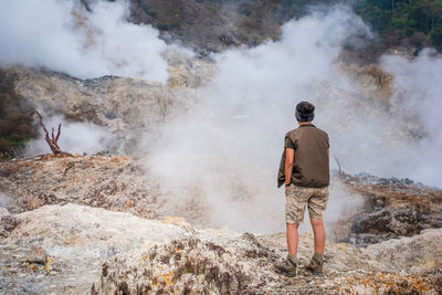 Rear view of man standing on volcanic landscape