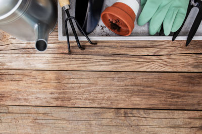 Gardening hobby flat lay with ceramic pot, pitchfork, shovel, gloves and dirt on wooden background