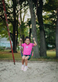 Portrait of cute girl sitting on swing at park