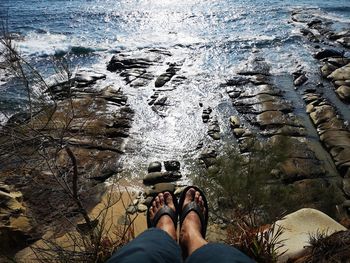 Low section of person on rock in sea