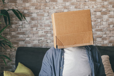 Man covering face with cardboard box at home
